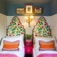 Children’s bedroom designed by Jo Bee featuring green headboards upholstered in Array Printed Fabric by Makoto Kagoshima, with vibrant hand-drawn florals on linen set against navy blue walls. Photography by Heidi Marfitt.